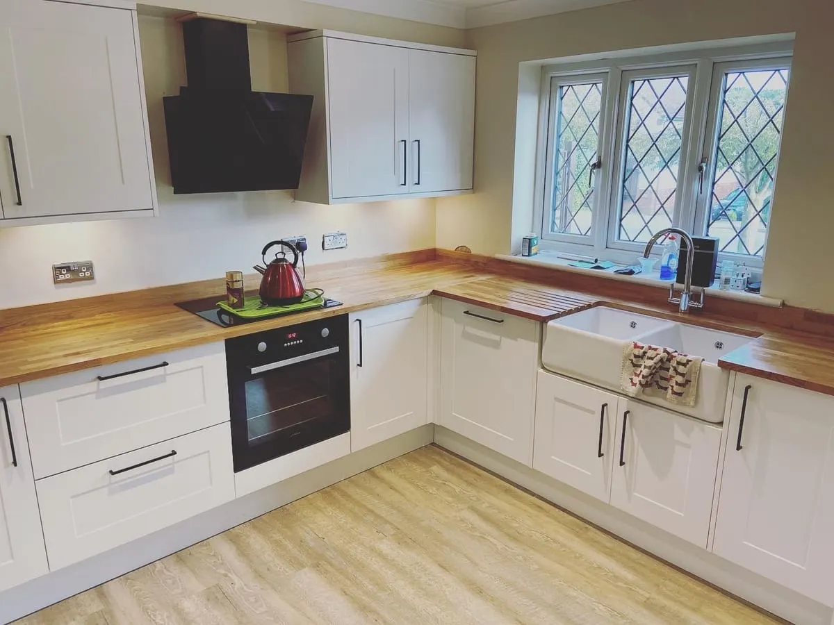 Cream shaker kitchen with solid oak worktops, ceramic butler sink under a leaded window and black extractor