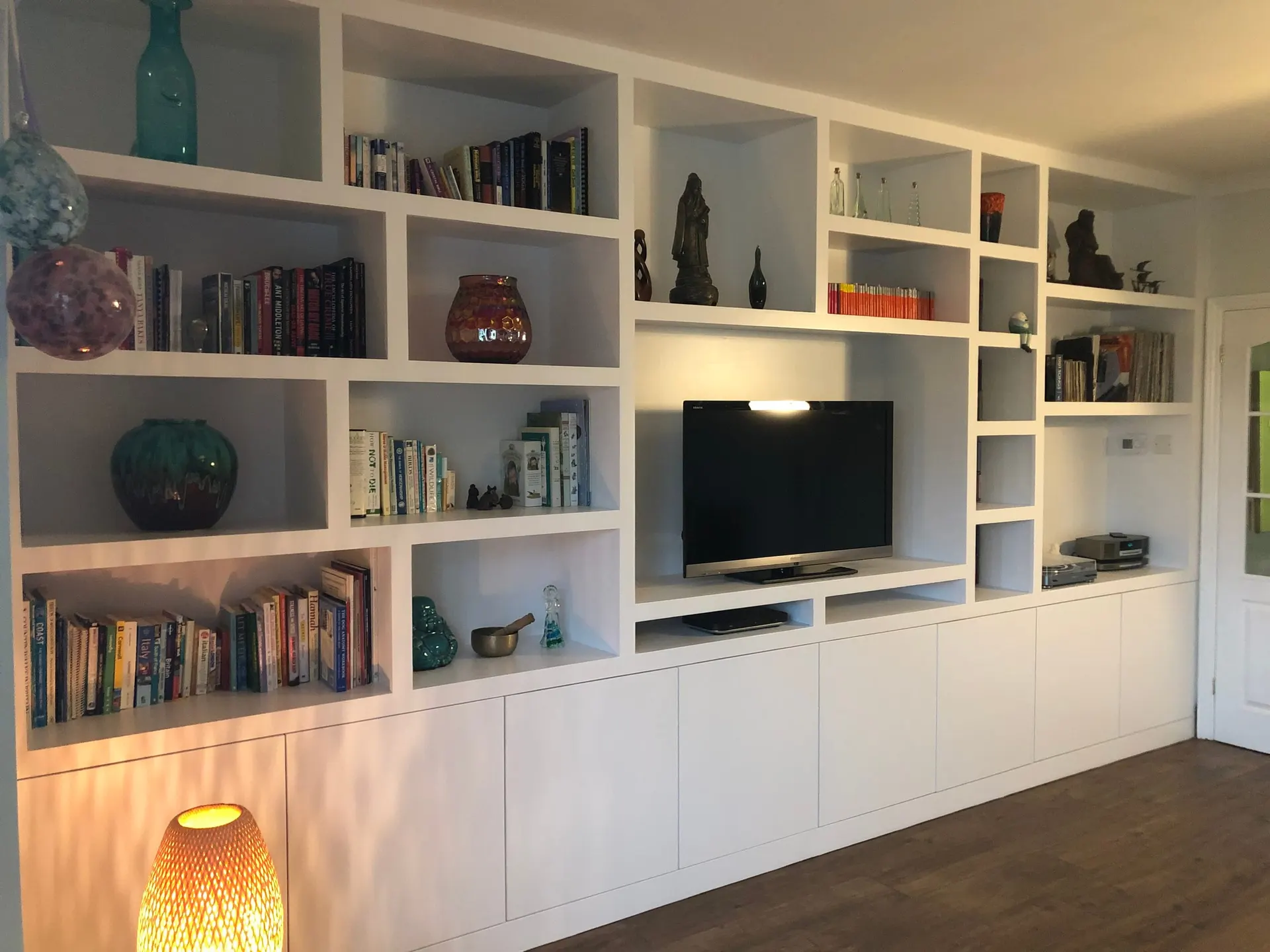 Full-Wall White Fitted Shelving Unit with Irregular Display Niches Full-wall white fitted shelving unit with irregular display niches, books, TV recess and base cupboards