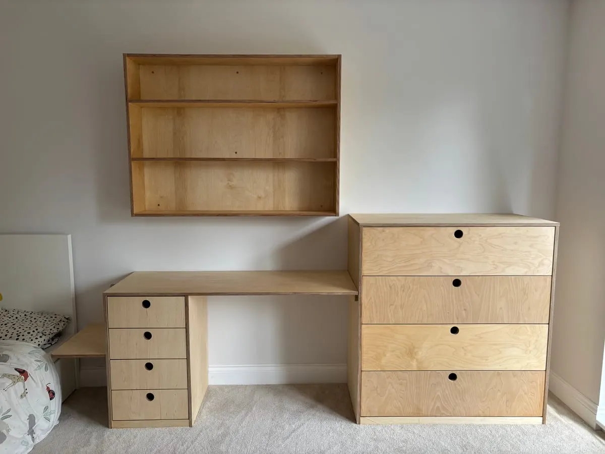 Birch plywood fitted desk, four-drawer chest and wall-mounted shelving unit in a child's bedroom