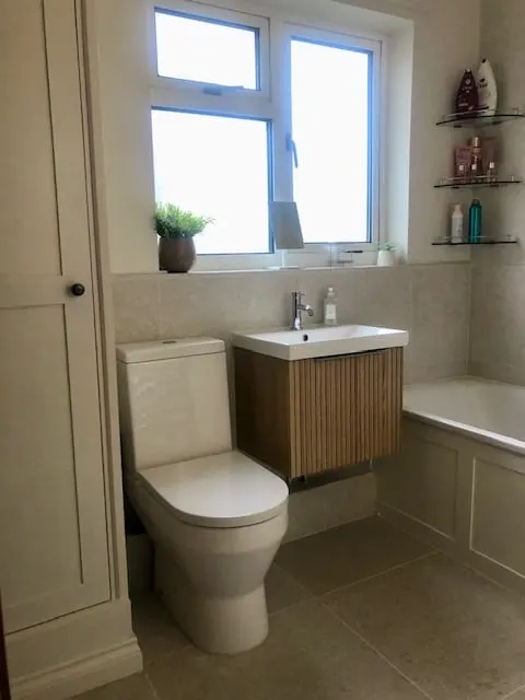 Bathroom with oak fluted wall-hung vanity, close-coupled toilet, panelled bath and tall airing cupboard