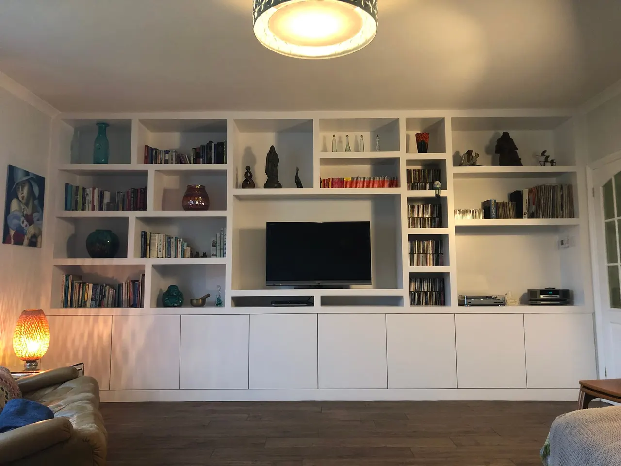 Full-width white fitted media wall with open bookshelves, TV recess and handleless base cupboards