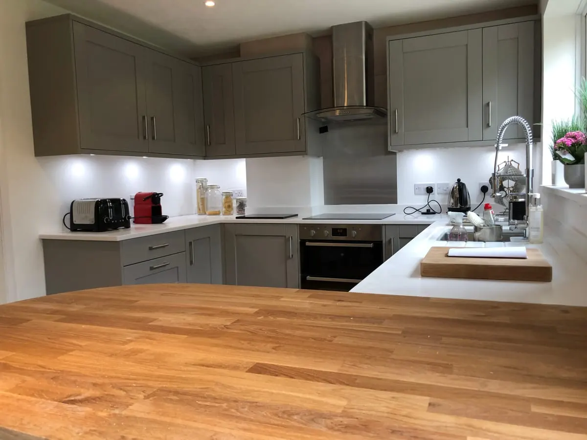 Grey shaker kitchen with white worktops, oak island top, chimney extractor and built-in oven