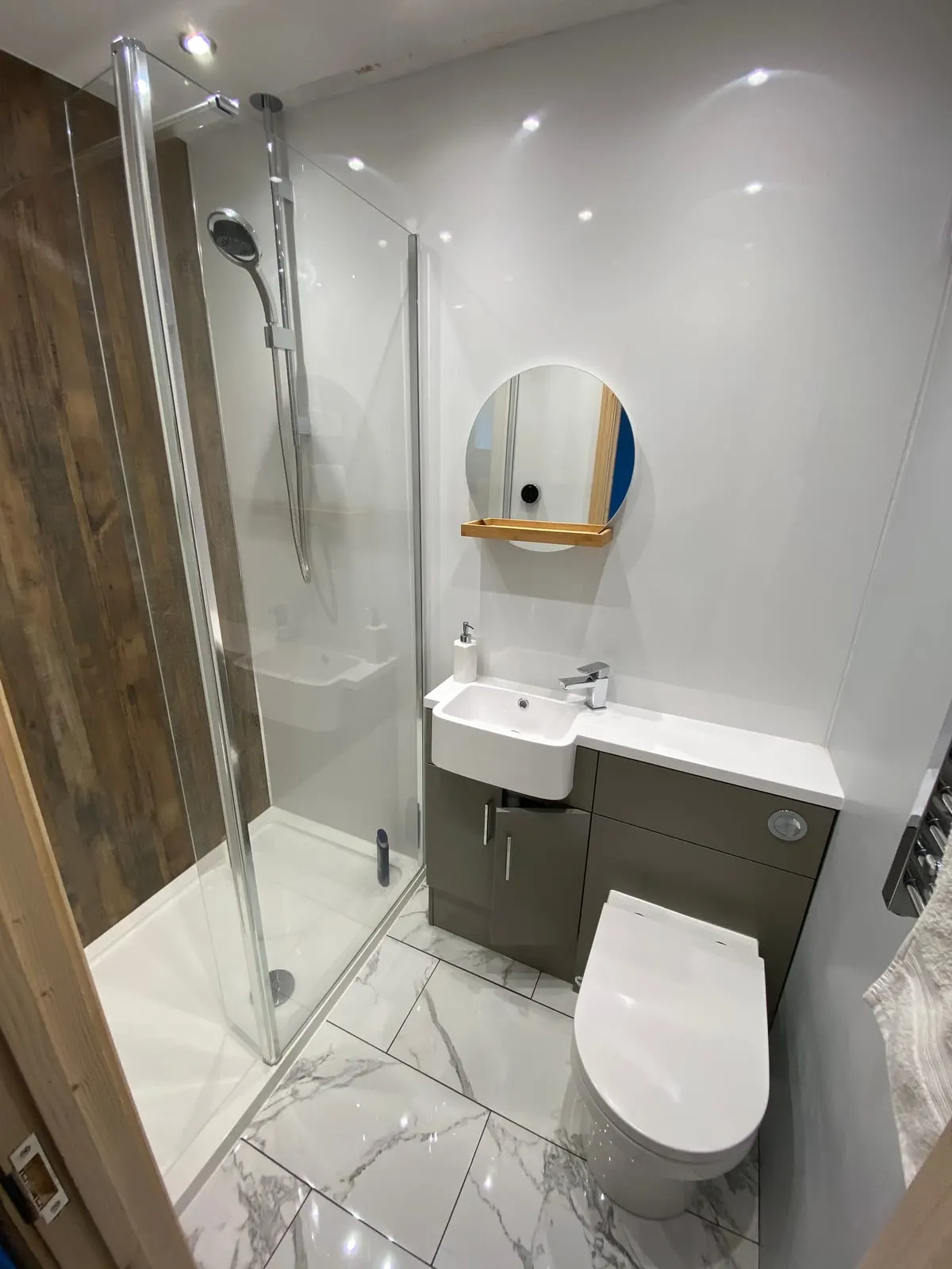 Shower room with glass enclosure, marble-effect tiling and a grey combined vanity and WC unit