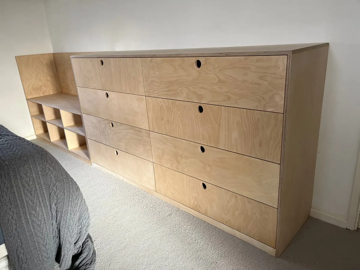 Birch plywood eight-drawer chest with cut-out handles and open cubby shelving in a carpeted bedroom